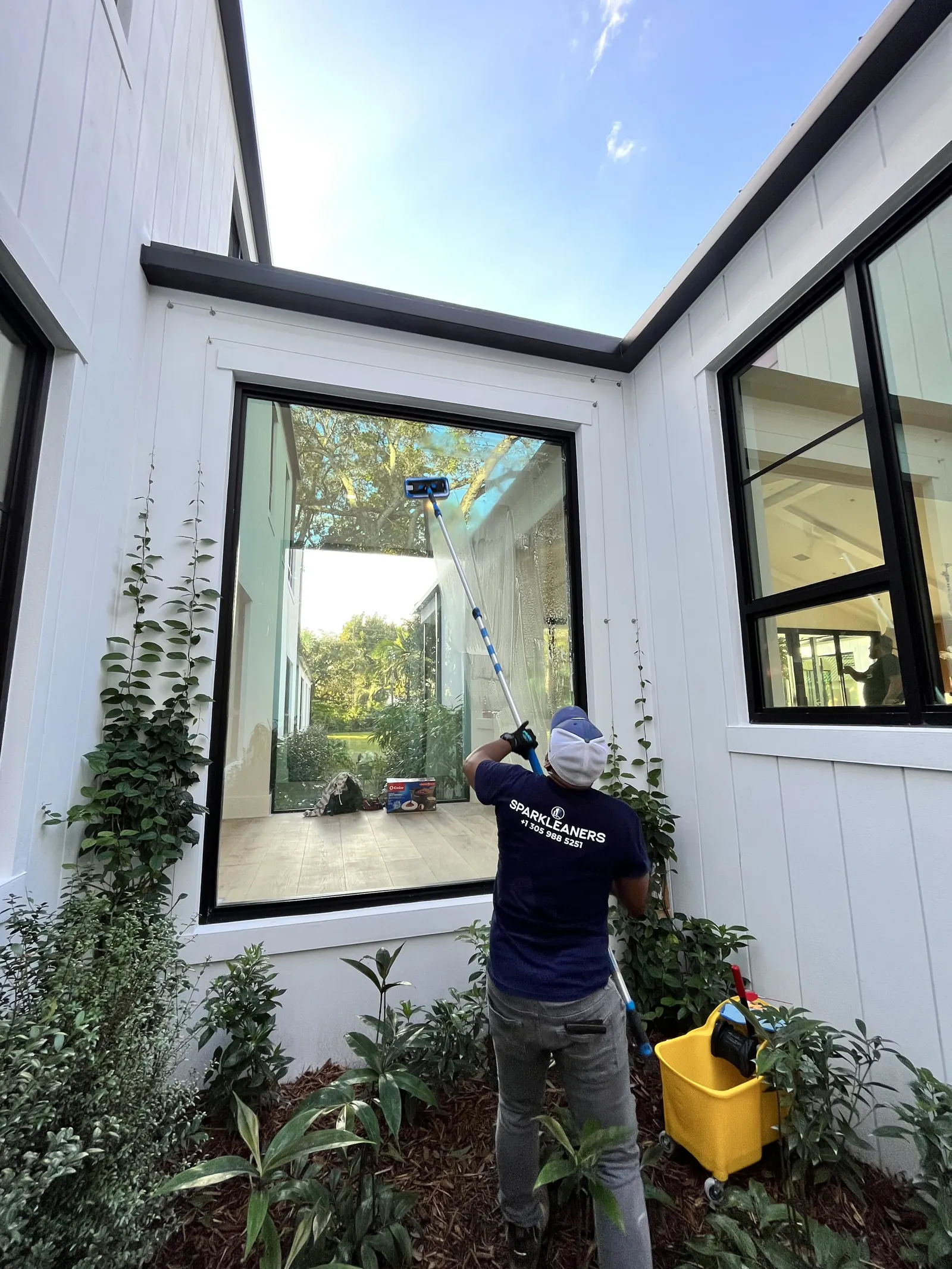 Sparkleaners team member cleaning exterior windows with a water-fed pole
